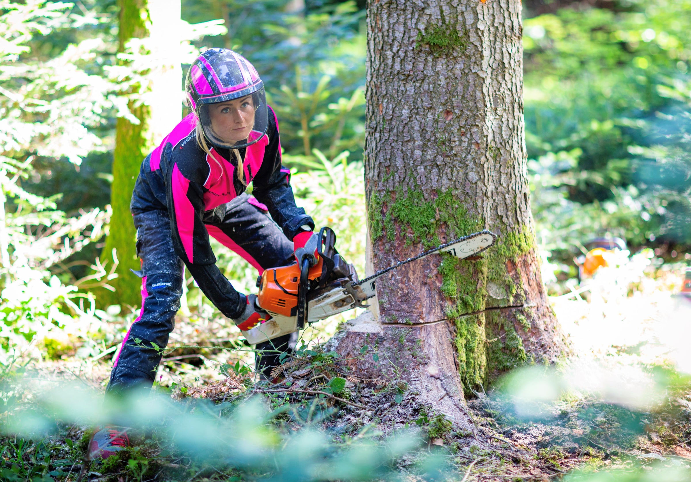 Frau mit Schutzhelm und Kettensäge